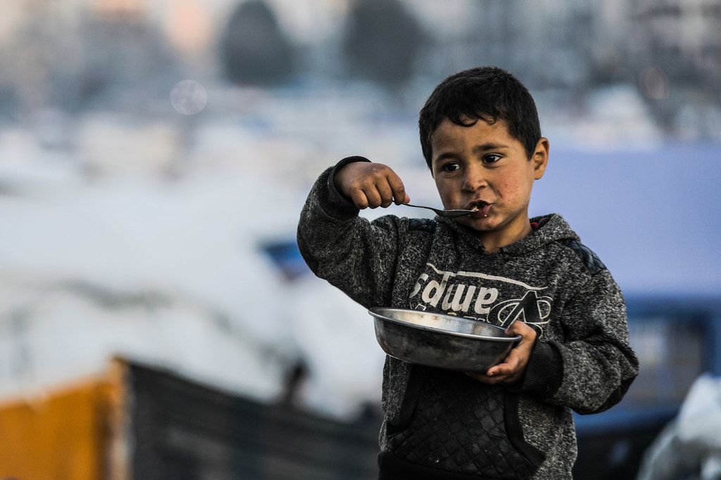 A young boy in Gaza City eats a plate of food.